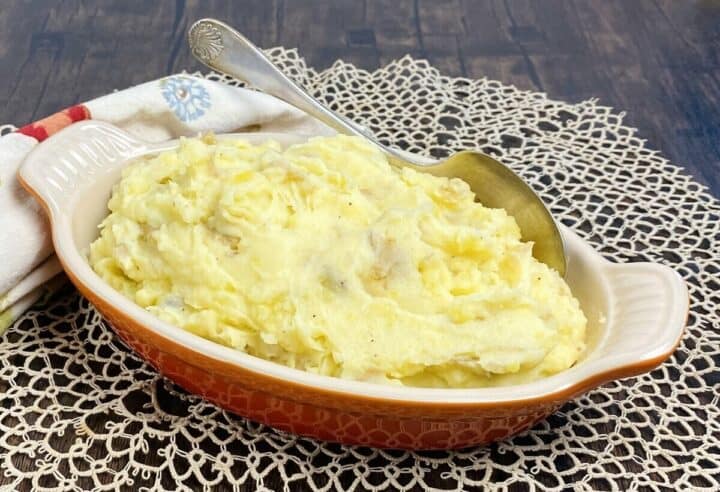 A dish of mashed potatoes with a spoon.