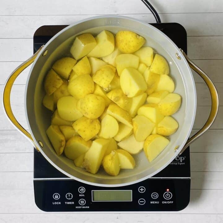 A pot filled with water and potatoes on a burner.