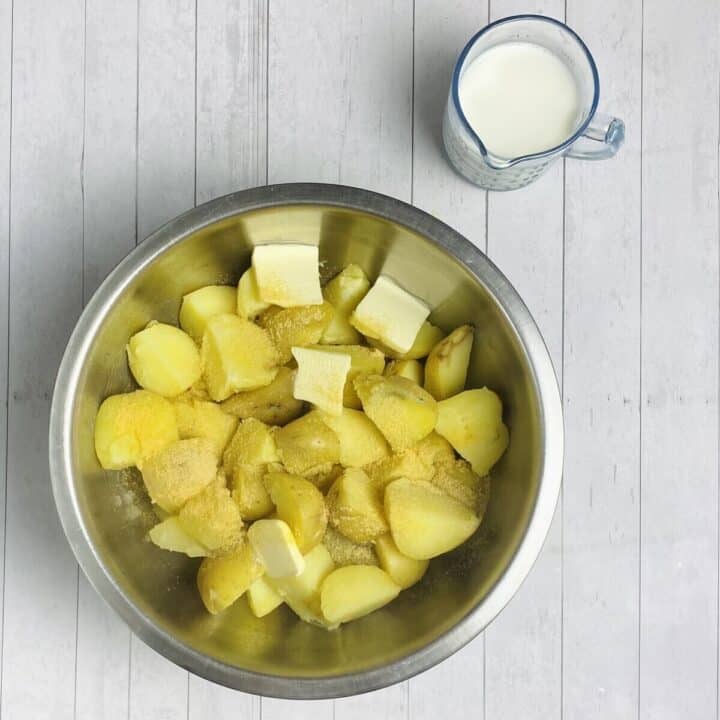 A bowl of cooked potatoes with milk, butter, and seasonings