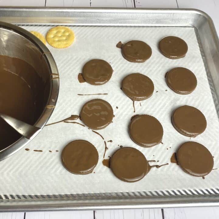 Ritz crackers coated in melted chocolate on parchment paper.