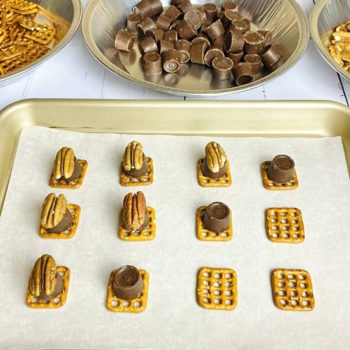 Pretzels, rolos, and pecans stacked on top of each other on a sheet pan.