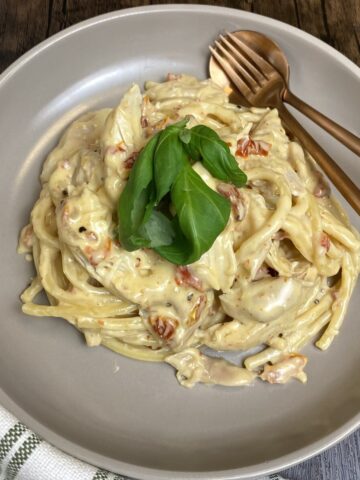 Bowl of marry me chicken pasta with fresh basil on top.