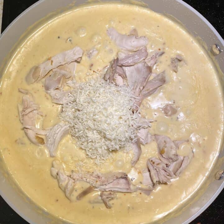 Cheese and chicken in a skillet sitting in marry me chicken sauce.