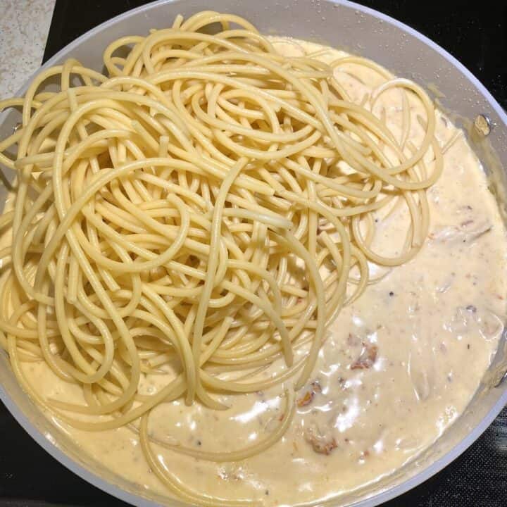 Pasta added on top of marry me chicken sauce in a skillet.