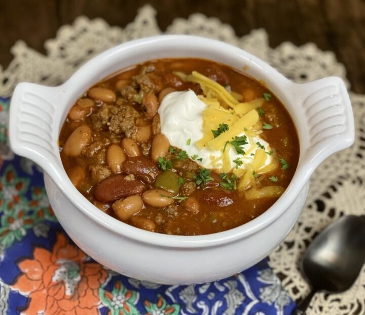 A small bowl filled with chili and topped with sour cream alongside a spoon and napkin.