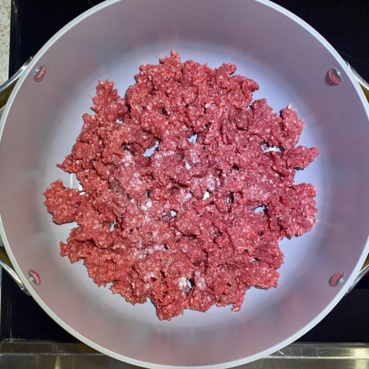 A pot with raw ground beef beginning to cook.