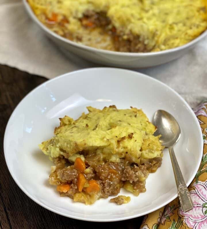 A serving of shepherds pie in a dish with a spoon and napkin.