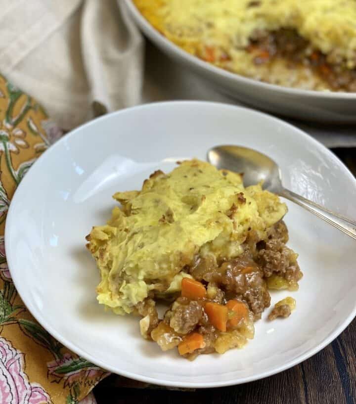 A serving of shepherds pie in a dish with a spoon and napkin.