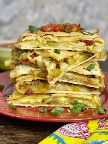 Five square potato quesadillas stacked up on a plate.