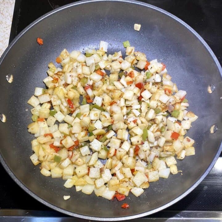 A skillet with o'brien hash browns cooking.