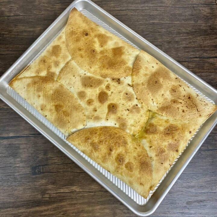 Quesadillas de papa fulling cooked sitting in a sheet pan.