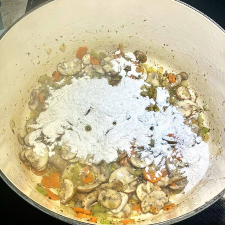 Flour added to a pot of cooked vegetables.