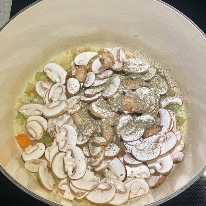 Mushrooms, seasonings, and vegetables sauteing in a pot.