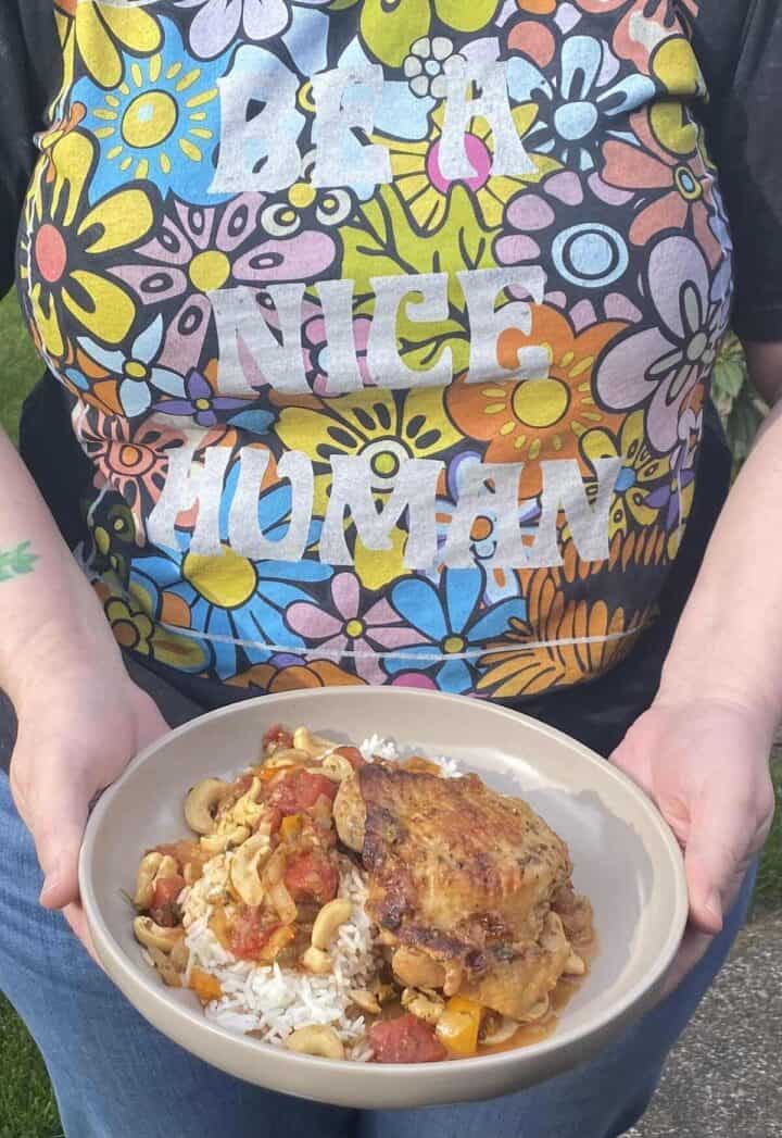 A person holding a bowl of cashew chicken.