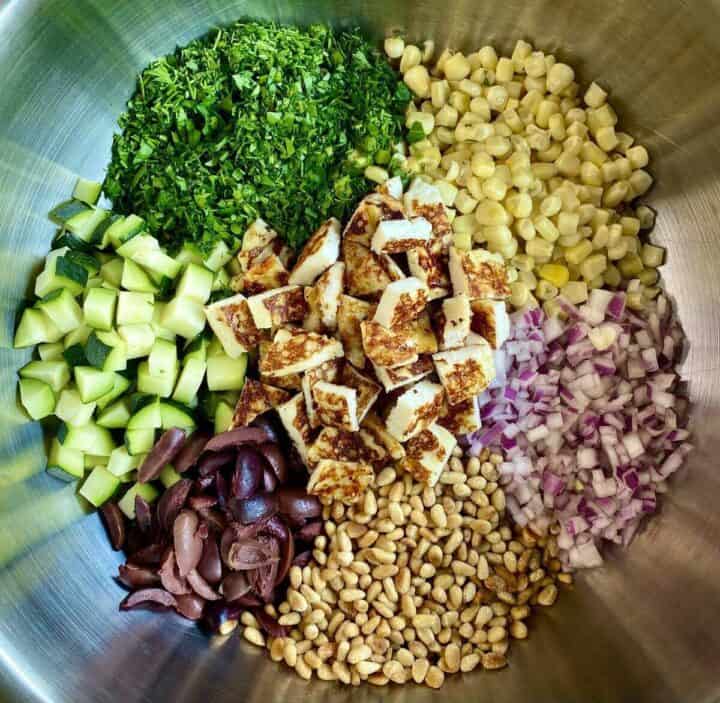A silver bowl full of salad ingredients.