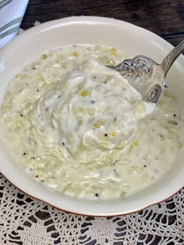 A bowl of leek sauce and a serving spoon.