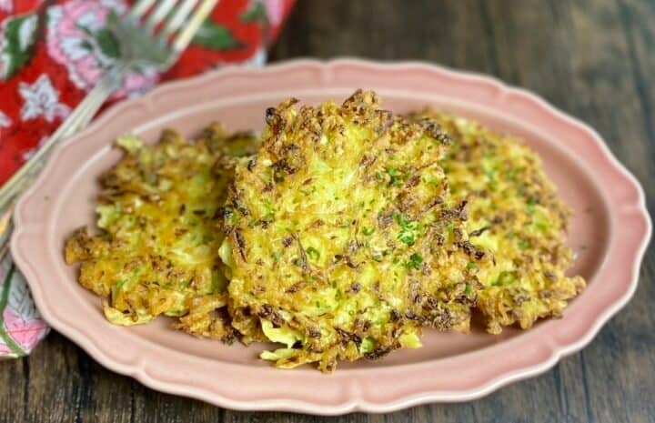 A closeup of 3 cabbage fritters on an oblong plate.