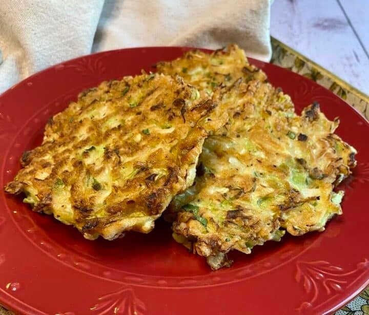 Three cabbage fritters shingled on a red plate.