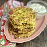 Golden cabbage fritter stacked on pink dish with cream dip.