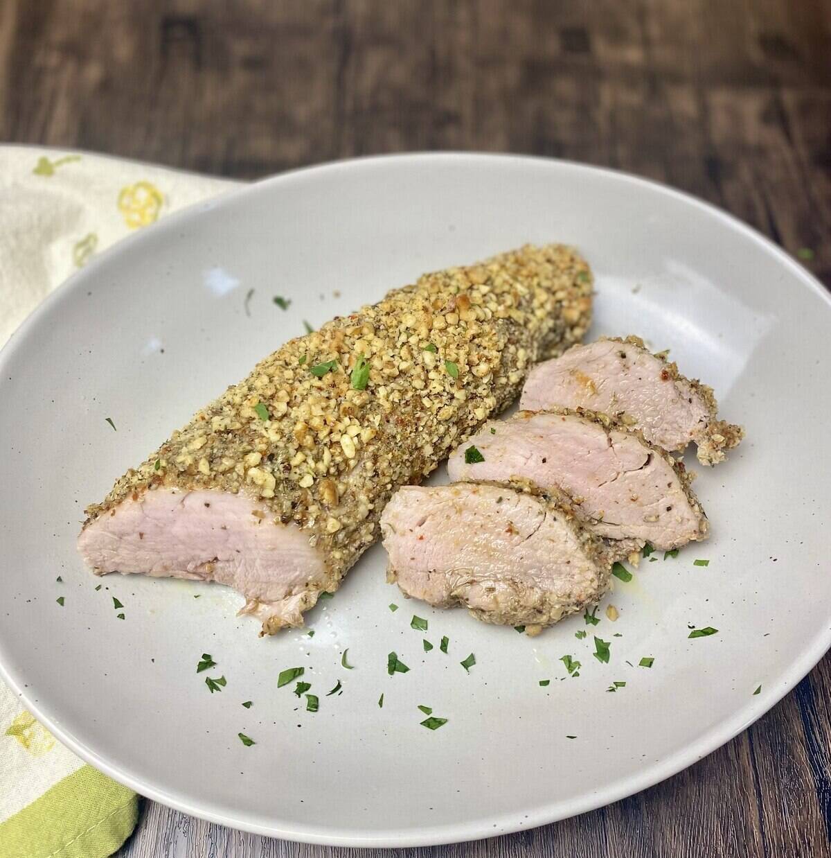 Walnut crusted pork tenderloin in a serving dish with a napkin.