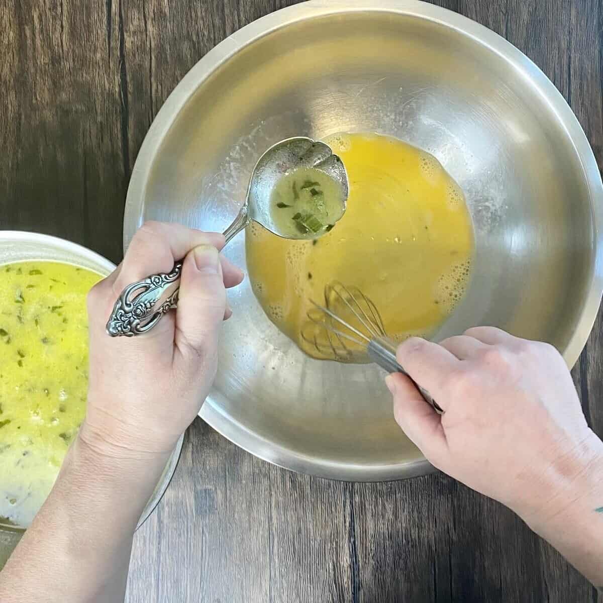 A hand ladeling hot broth into a bowl of eggs.