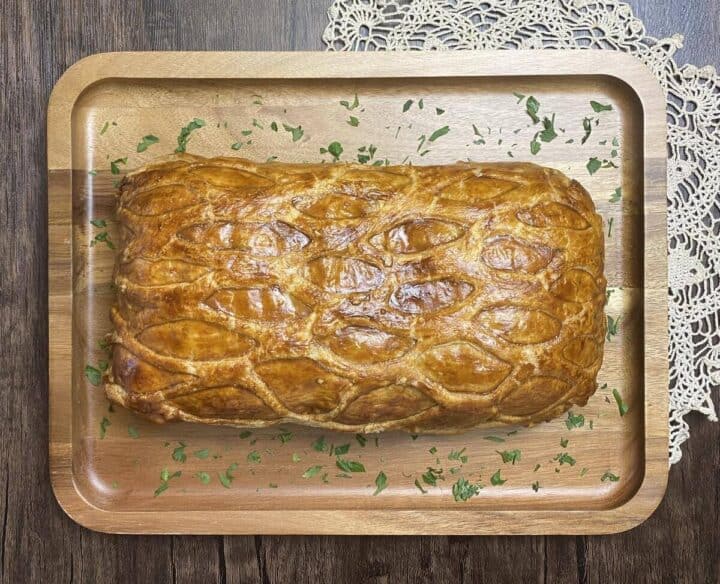 A baked vegetable wellington on a wooden platter.