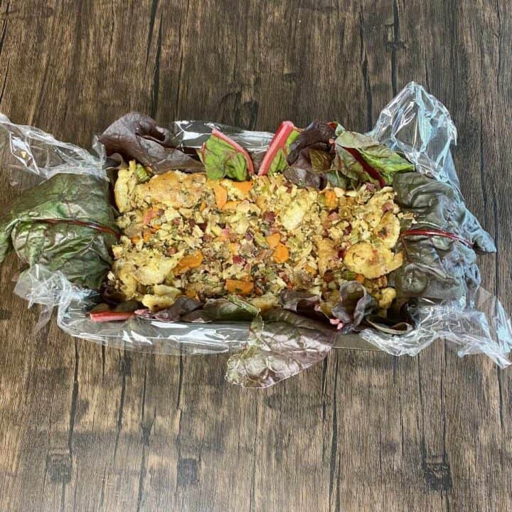 Plastic wrap-lined loaf pan filled with wellington stuffing ingredients.