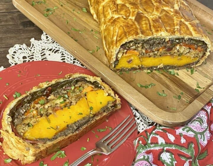 A slice of vegetable wellington on a plate with a fork.