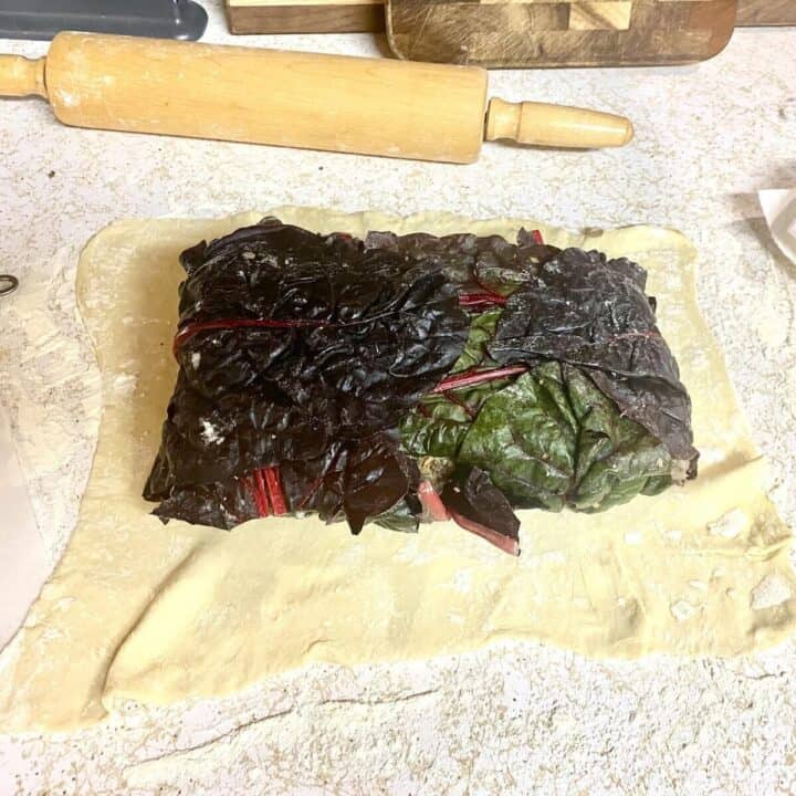 A vegetable loaf on a sheet of puff pastry and a rolling pin.