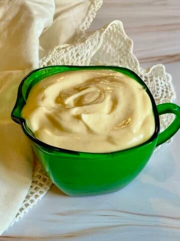 green pitcher filled with garlic aioli and a napkin.