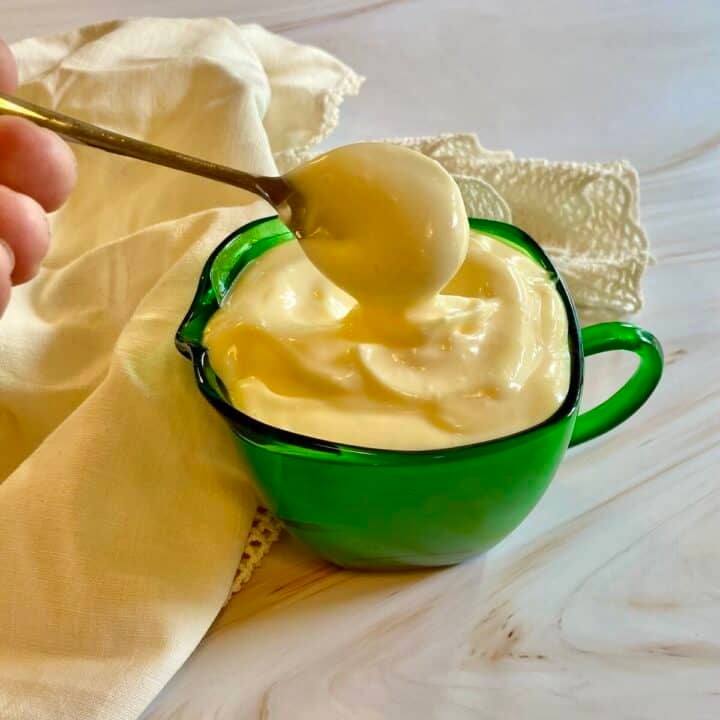 A green bowl of garlic aioli with a spoon and napkin.